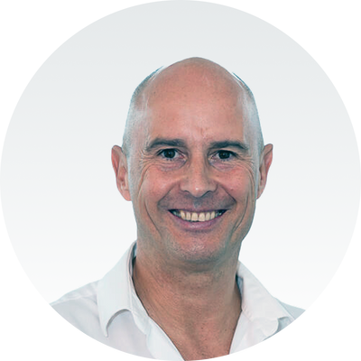 Eine lächelnde Person in weißem Hemd vor grauem Hintergrund, präsentiert von Master Ch.