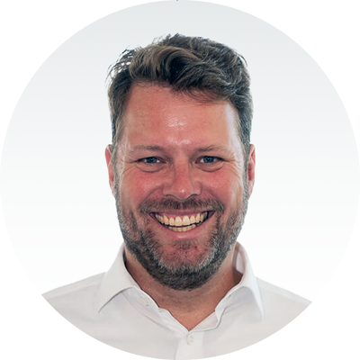 Ein lächelnder Mann in weißem Hemd vor grauem Hintergrund, Markenname Master Ch.