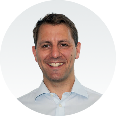 Ein lächelnder Mann in weißem Hemd vor grauem Hintergrund, Markenname Master Ch.