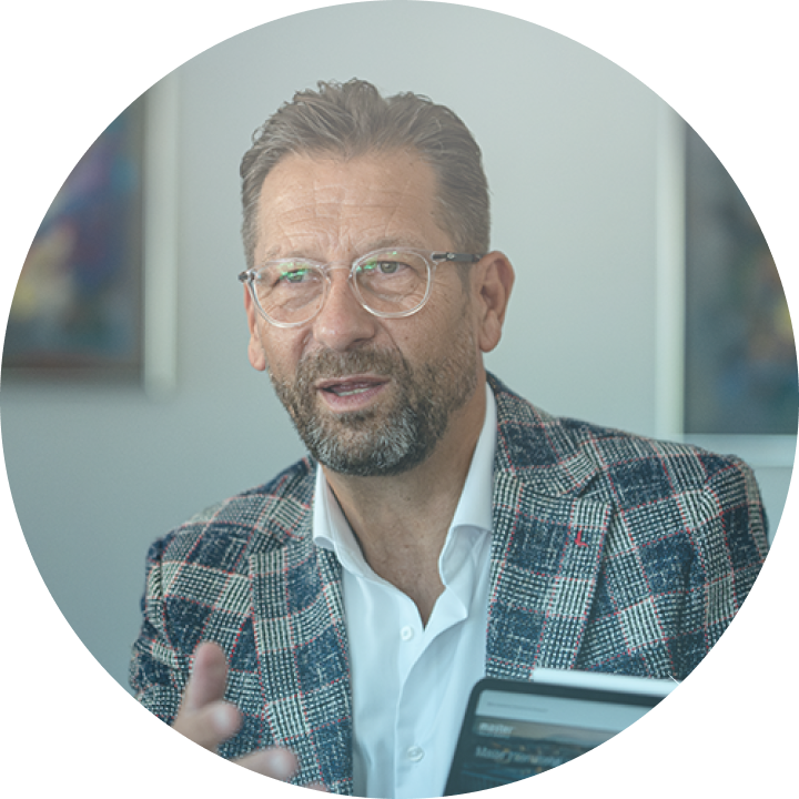 Ein Mann im karierten Sakko spricht in einem Büro, Master Ch Laptop sichtbar.