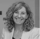 Eine lächelnde Frau mit lockigem Haar trägt einen Blazer, Master Ch.