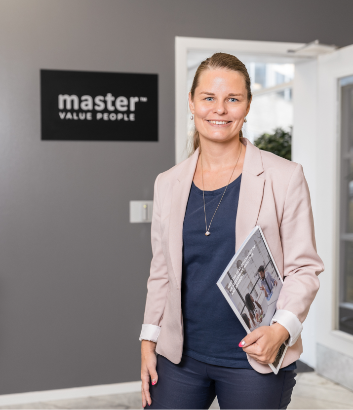 Eine Frau in Businesskleidung steht vor einem Master Ch Firmenschild.